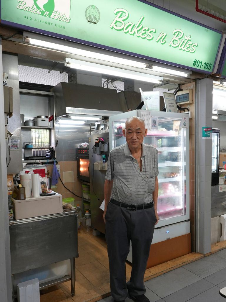 Christopher, co-owner of Bakes n Bites, standing at his stall in Old Airport Road Food Centre